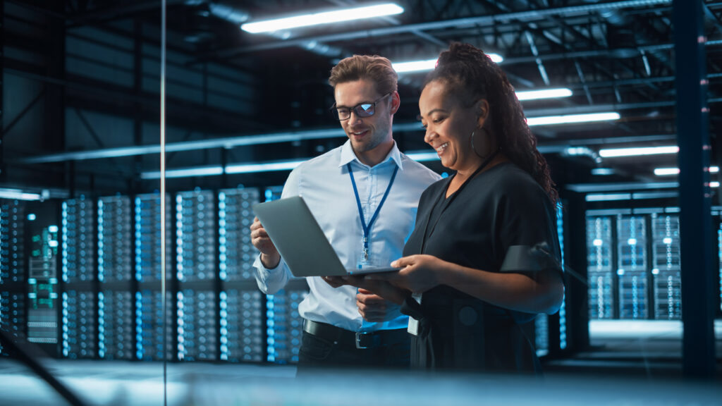 IT professional with laptop standing in server data center - Data Center & Cloud
